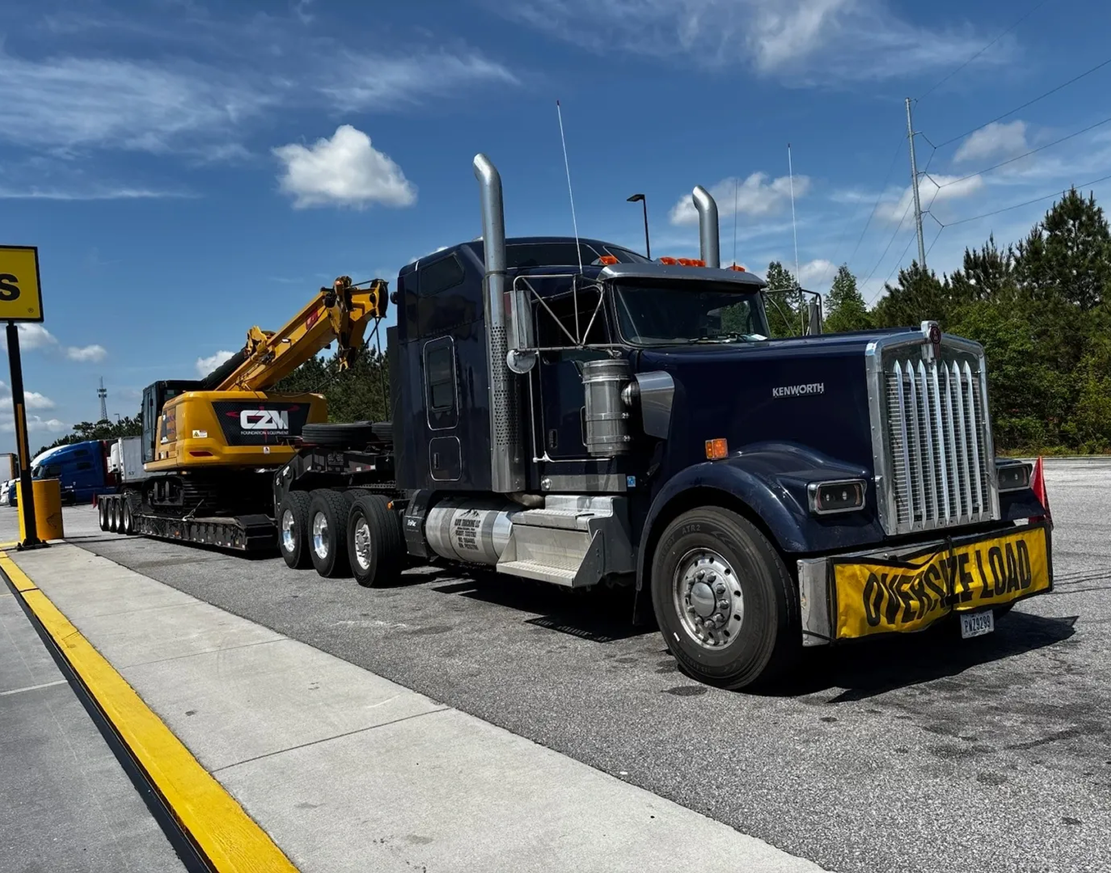 Truck towing construction equipment on highway.