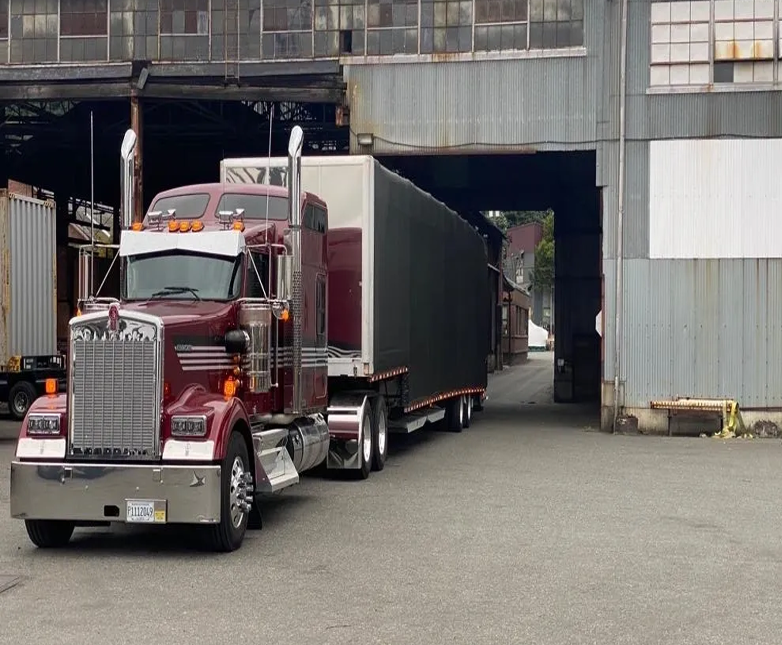 Red truck exiting industrial building loading dock.