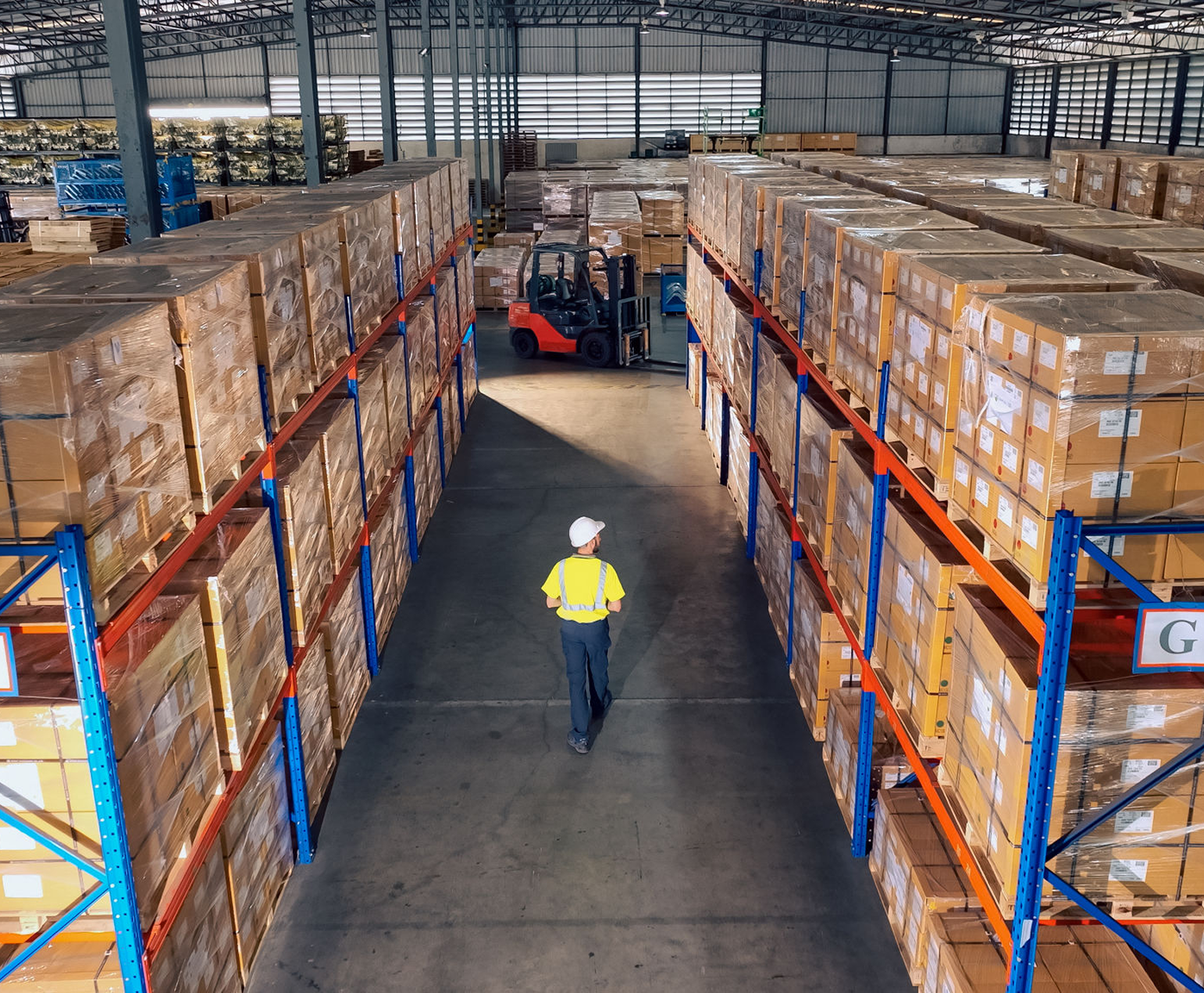 Warehouse worker walking between tall shelves.