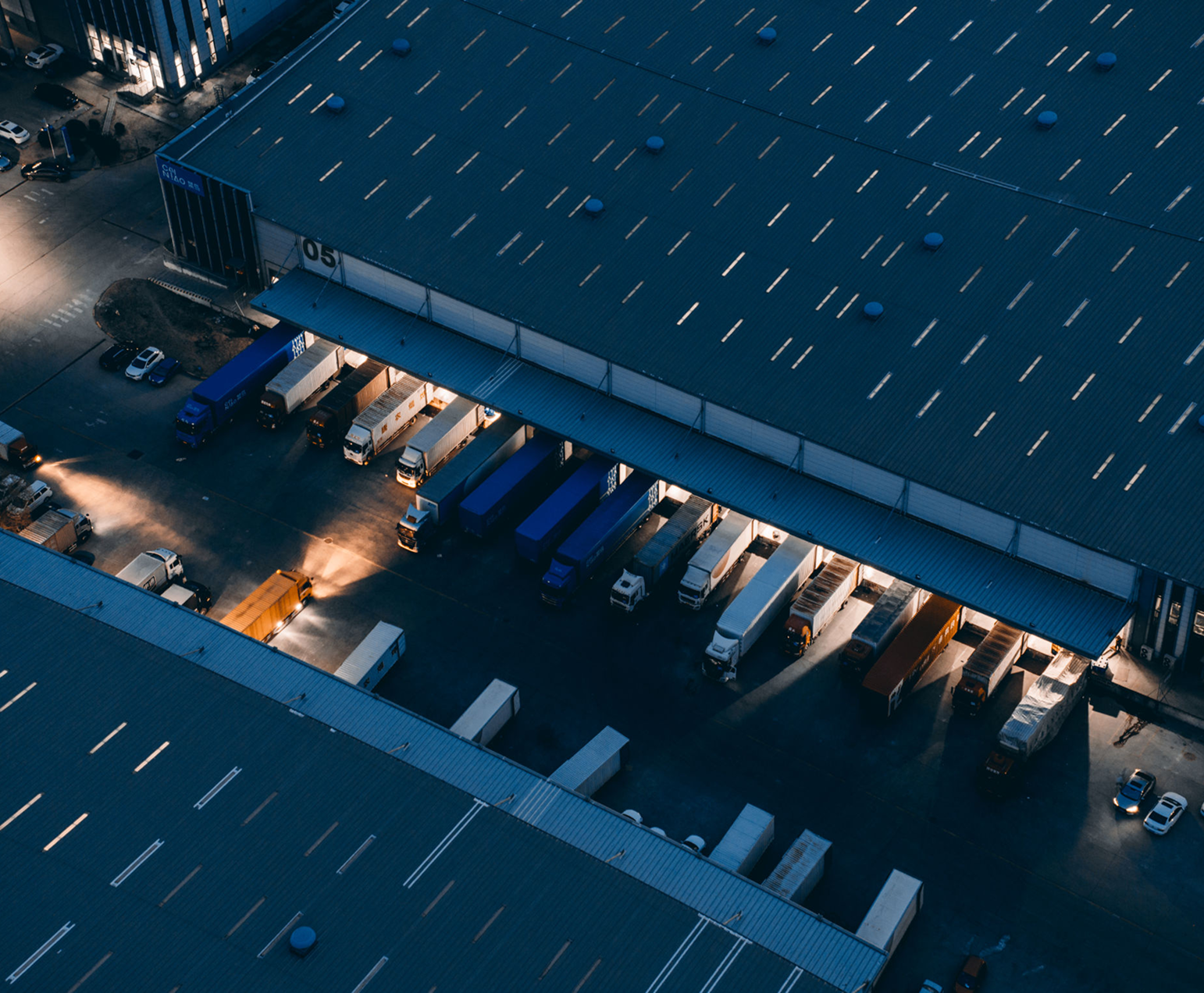 Aerial view of warehouse with parked trucks.